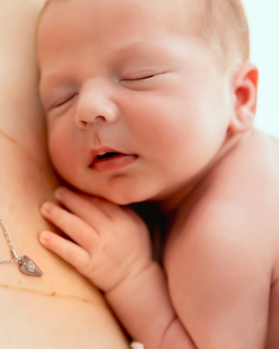Nouveau-né endormi paisiblement dans les bras de sa maman, séance photo professionnelle, photographe nouveau-né à Annemasse