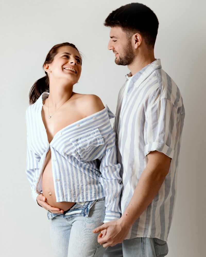 Couple heureux attendant un bébé, femme enceinte en chemise rayée avec son partenaire en studio photo, photographe grossesse près de Genève