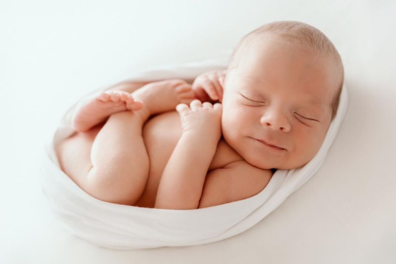 Bébé nouveau-né endormi emmailloté blanc en studio photo, spécialité photographe Annemasse, entre Genève et Annecy