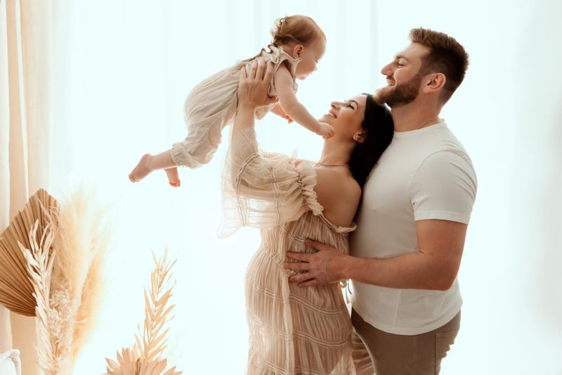 Famille heureuse avec bébé en studio, mère enceinte et père souriants lors d'une séance photo professionnelle, photographe famille près de Genève