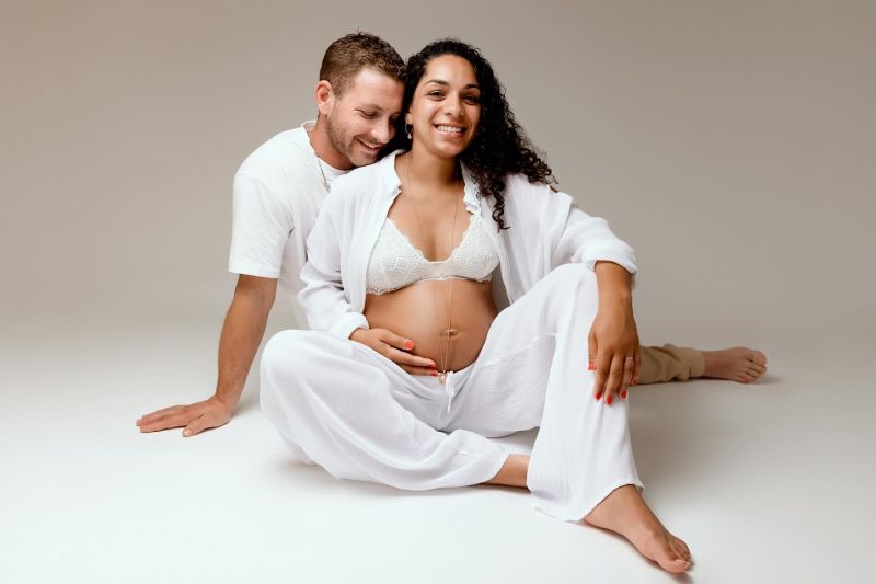 Couple heureux lors d'une séance photo grossesse professionnelle en studio, femme enceinte et futur papa en tenues, photographe grossesse en Haute-Savoie