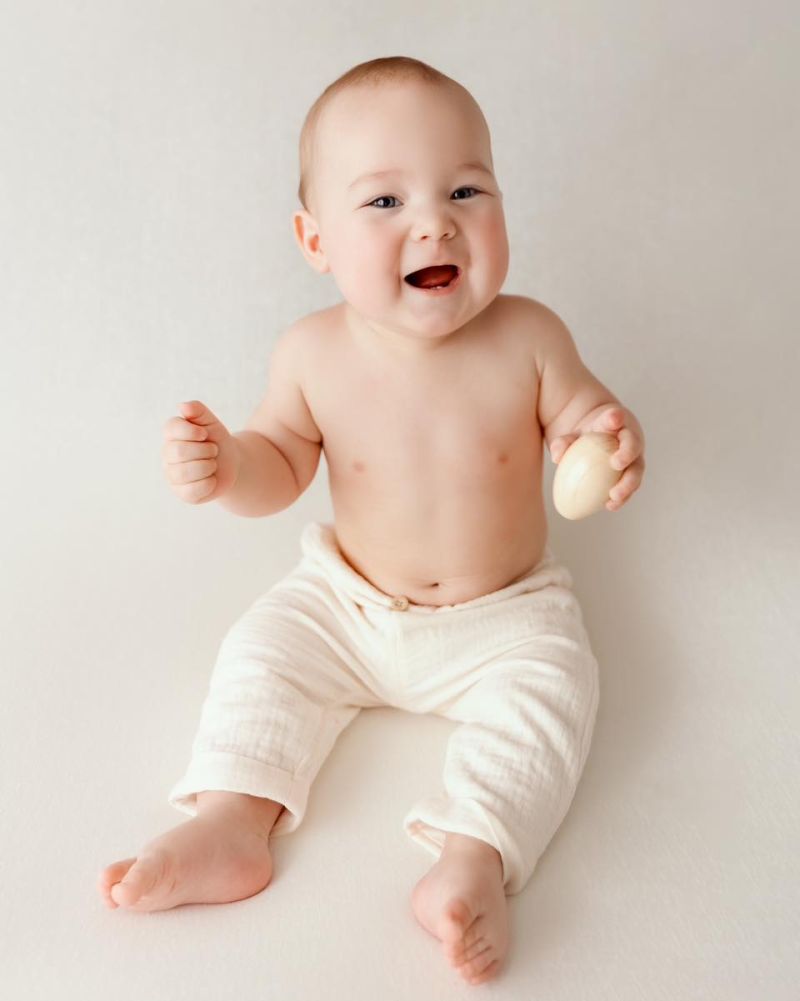 Bébé joyeux riant, portrait studio professionnel en lumière naturelle sur fond blanc neutre, photographe bébé à Annemasse