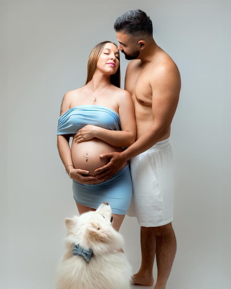 Couple attendant un bébé photographié en studio avec tendresse, accompagné de leur chien blanc, photographe grossesse à Annemasse, près de Genève