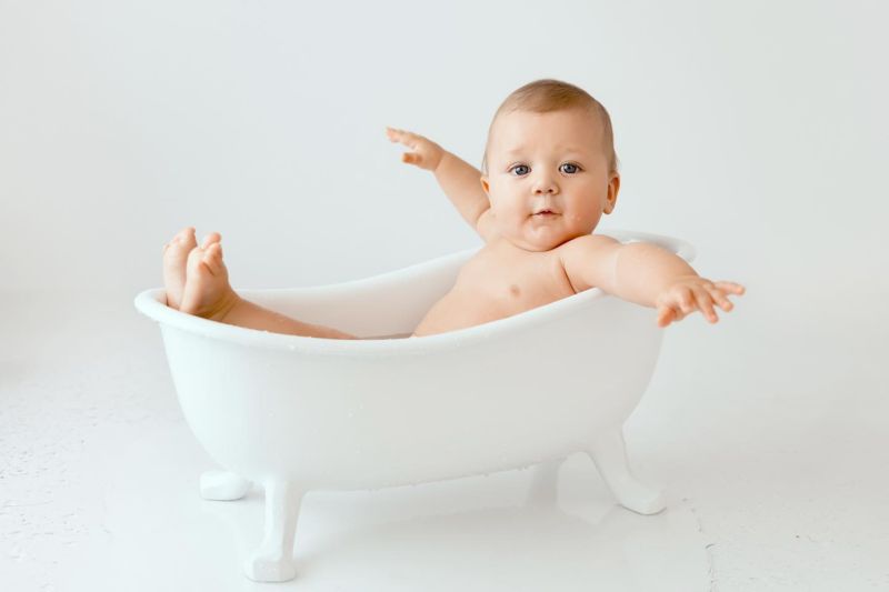 Bébé souriant dans une baignoire blanche, séance photo studio professionnelle, photographe bébé en Haute-Savoie