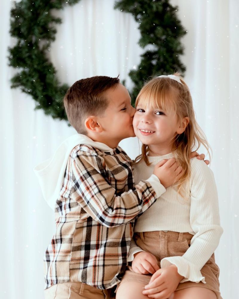Deux enfants souriants s'embrassant devant décoration de Noël en studio photo près de Genève