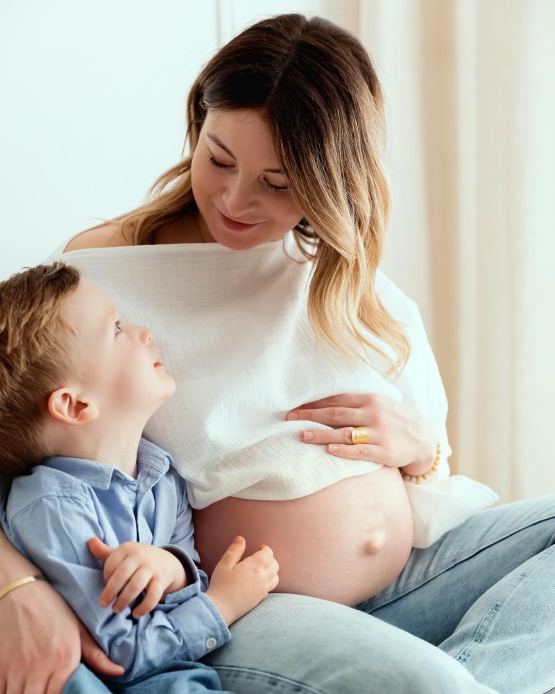 Femme enceinte souriante avec son enfant en studio photo, photographie grossesse tendresse et intimité, photographe grossesse en Haute-Savoie
