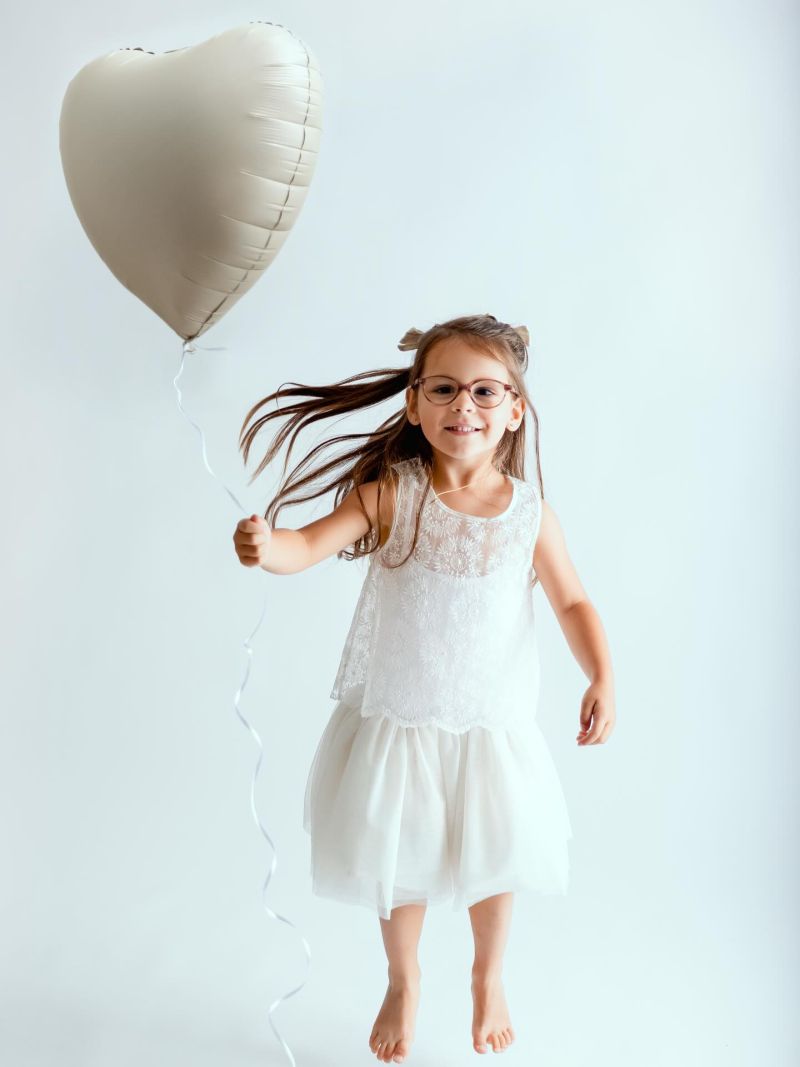Jeune fille en robe blanche souriante tenant un ballon cœur blanc, photo portrait studio professionnel, photographe en Haute-Savoie