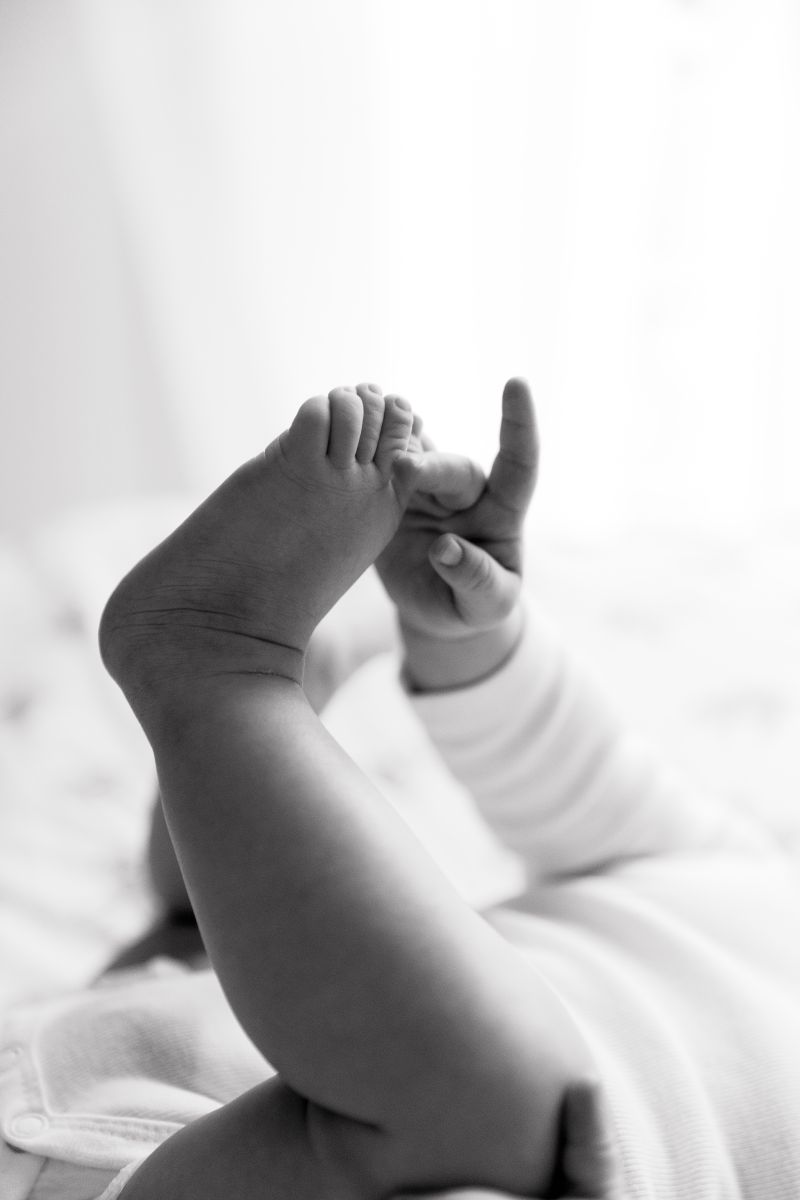 Gros plan tendres sur les petits pieds et mains d'un nouveau-né en noir et blanc, prise en studio, photographe bébé à Annemasse