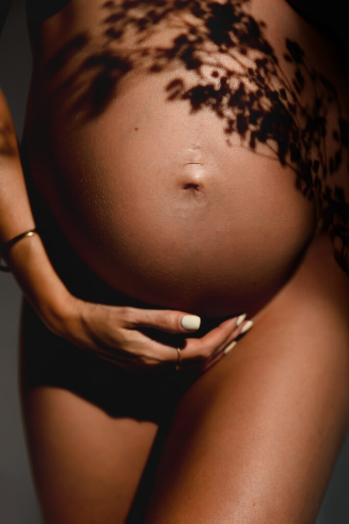 Portrait of a mum-to-be holding her bump in lace, intimate maternity photography in Annemasse