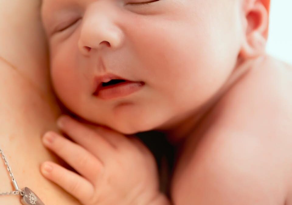 Nouveau-né endormi paisiblement dans les bras de sa maman, séance photo professionnelle