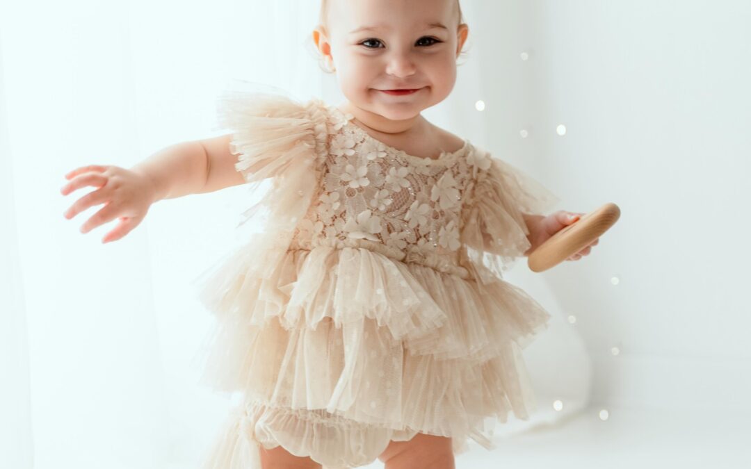 Bébé fille joyeux en robe tulle beige clair posant en studio avec bokeh lumineux, photographe bébé spécialisée Annemasse
