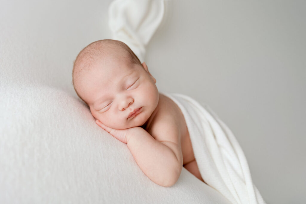 Nouveau-né endormi enveloppé de blanc, séance naissance au studio d'Annemasse