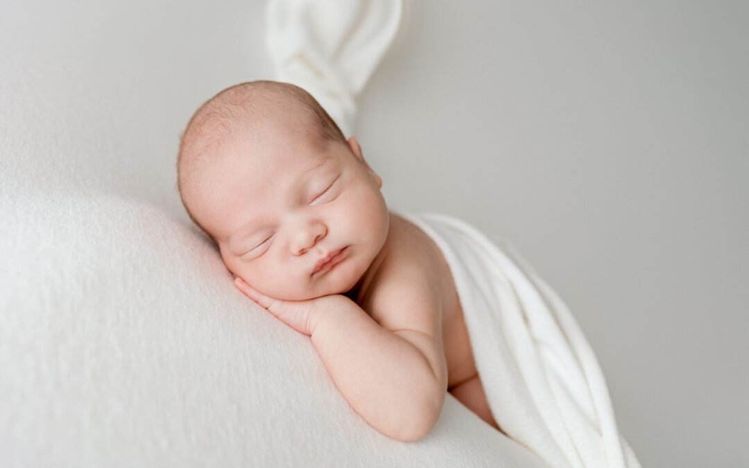 Nouveau-né endormi enveloppé de blanc, photographe spécialisée naissance Annemasse