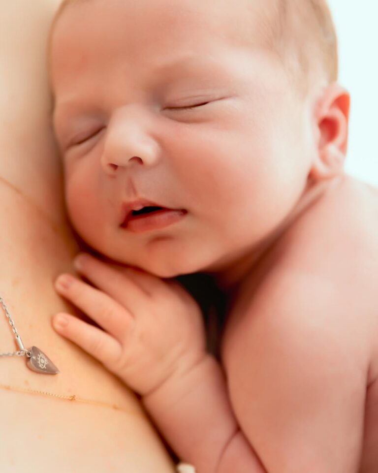 Nouveau-né endormi paisiblement dans les bras de sa maman, séance photo professionnelle