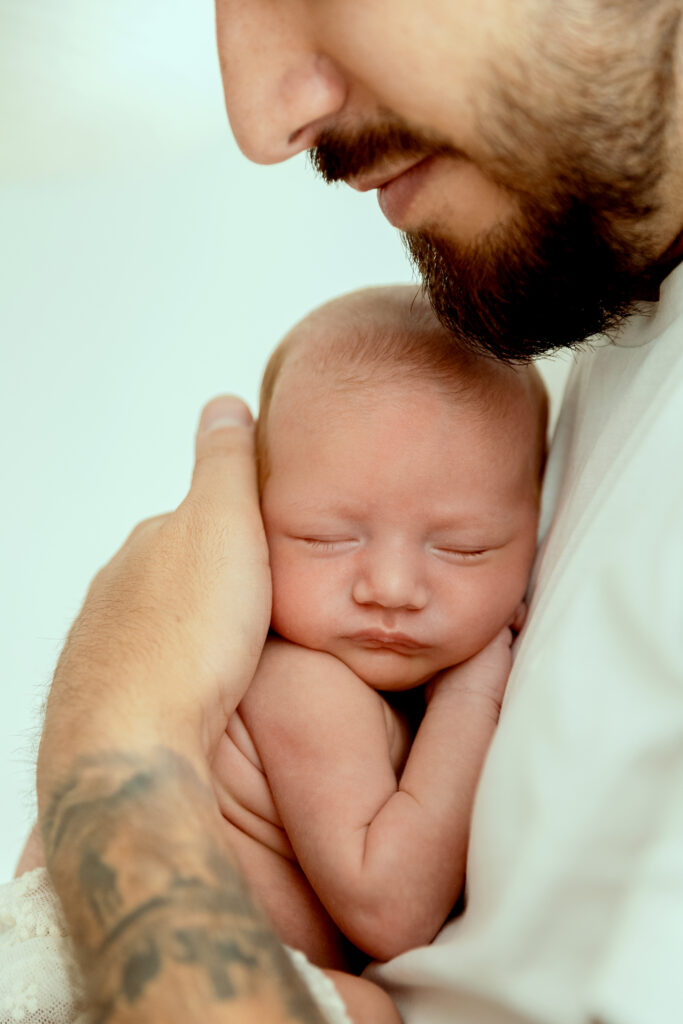 Portrait tendre père barbu tenant nouveau-né endormi dans ses bras, photographie naissance Mlle L Photographie