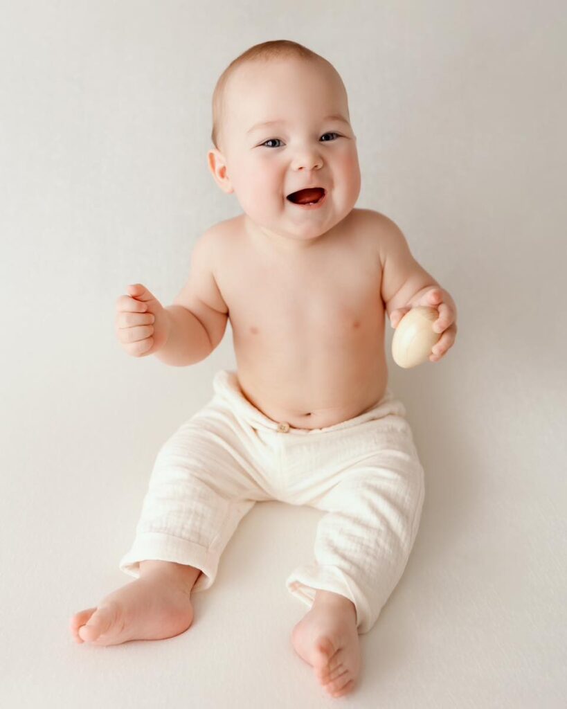 Bébé joyeux riant, portrait studio professionnel en lumière naturelle sur fond blanc neutre, photographe bébé à Annemasse