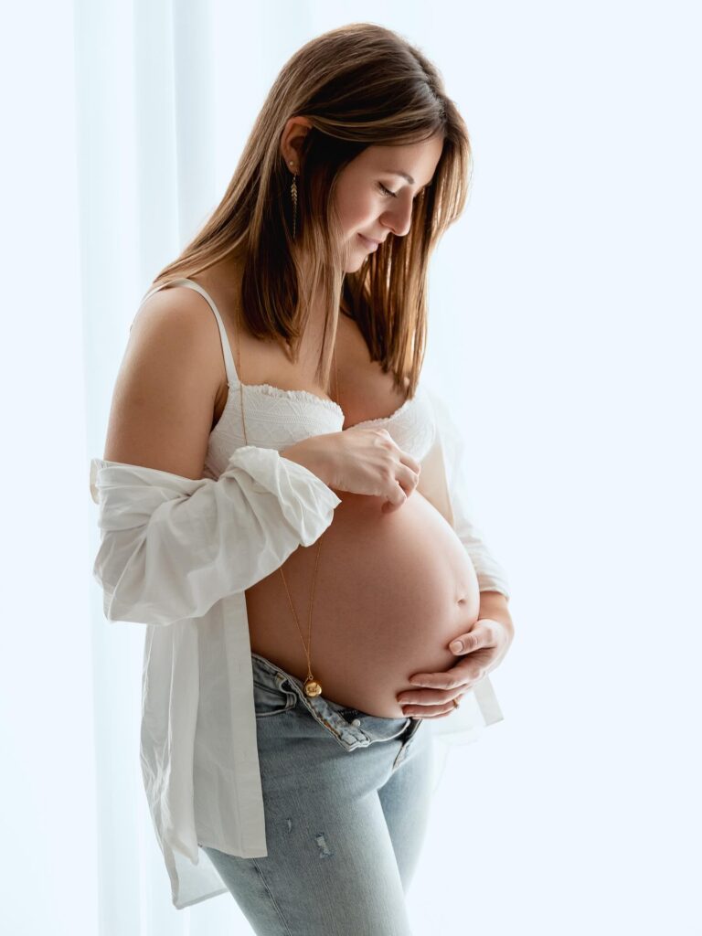Mum-to-be in a white shirt and jeans holding her bump